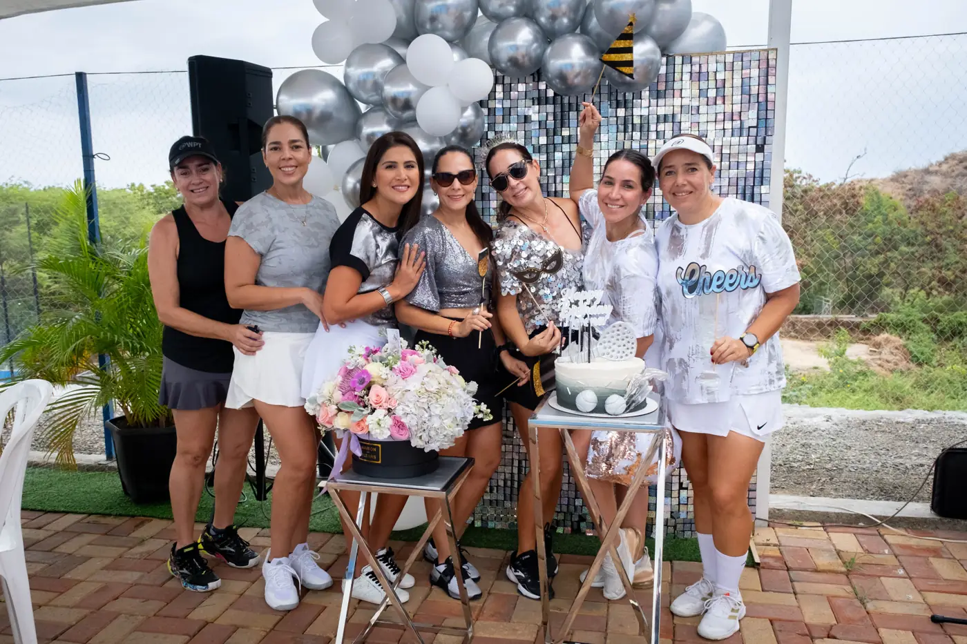 Grupo de amigas celebrando un cumpleaños con pastel y globos en Padelmar