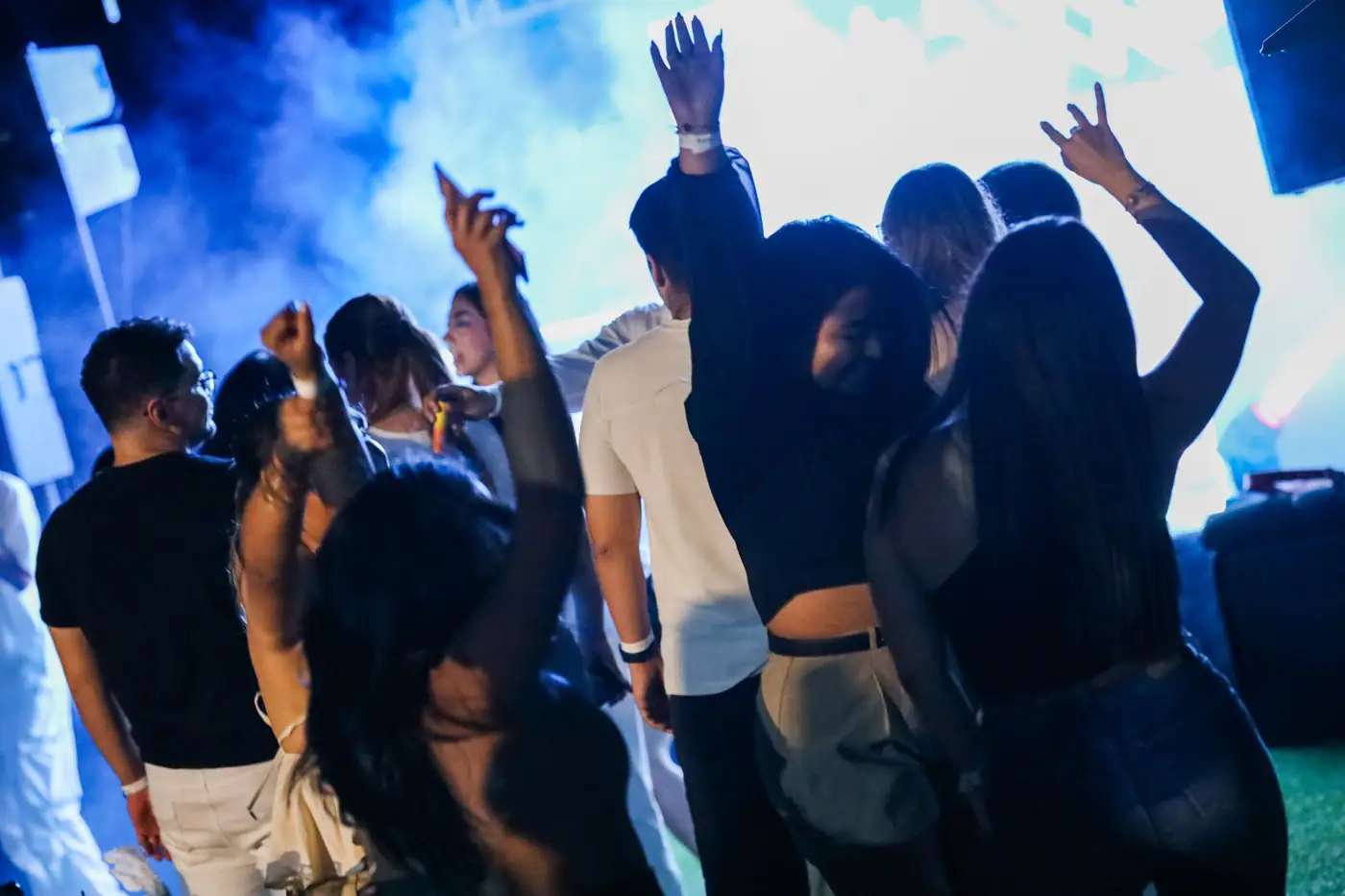 Invitados bailando de noche frente a la pantalla en Padelmar Gardens
