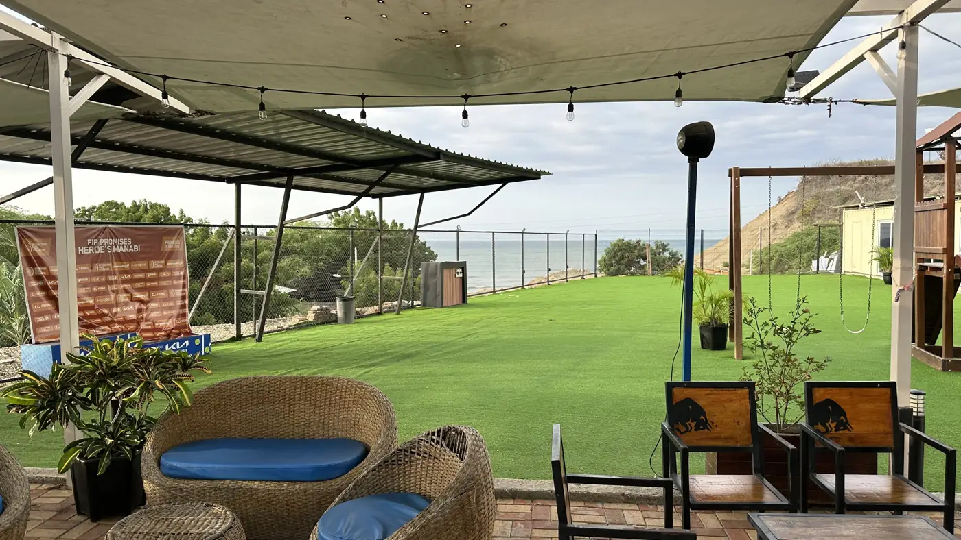 Salas de mimbre y césped de Padelmar Gardens con el mar al fondo