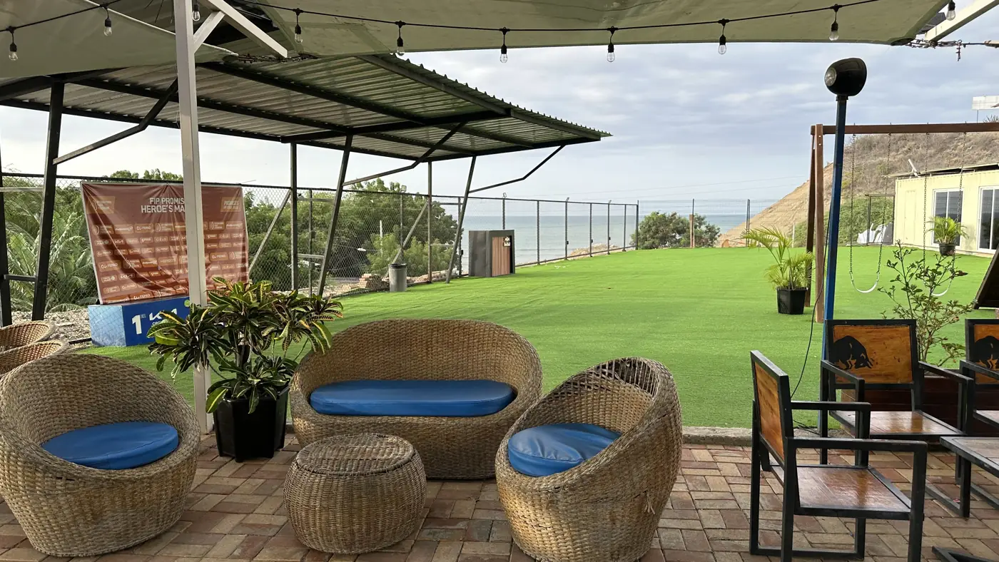 Sala de mimbre y jardín con vista al mar, con columpios al fondo