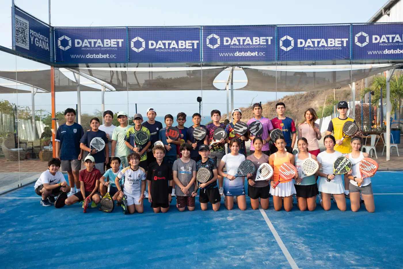 Grupo de niños y jóvenes de la academia posando con sus paletas en la cancha
