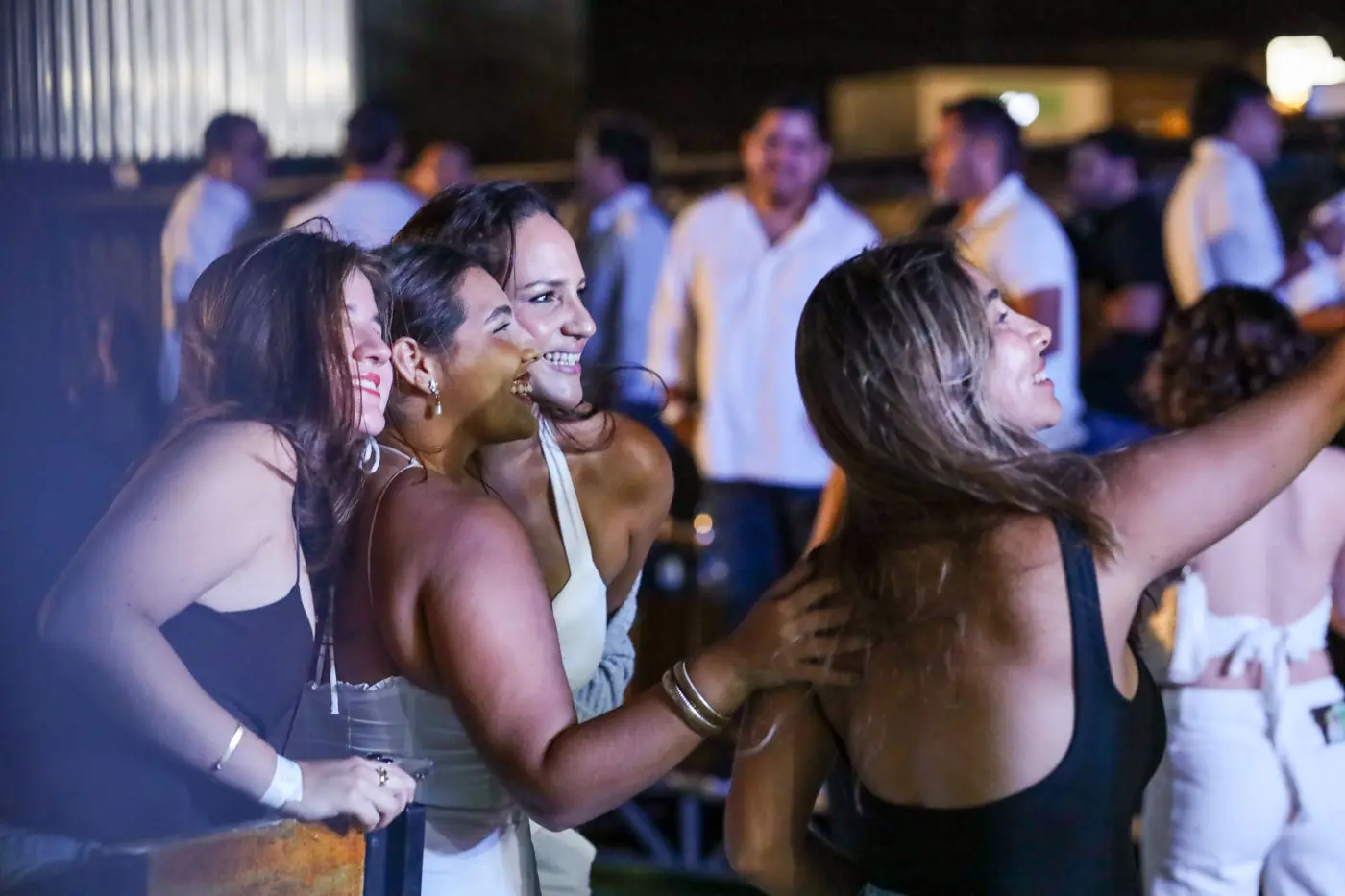 Grupo de amigas sonriendo y tomándose una foto en una noche de fiesta en el jardín