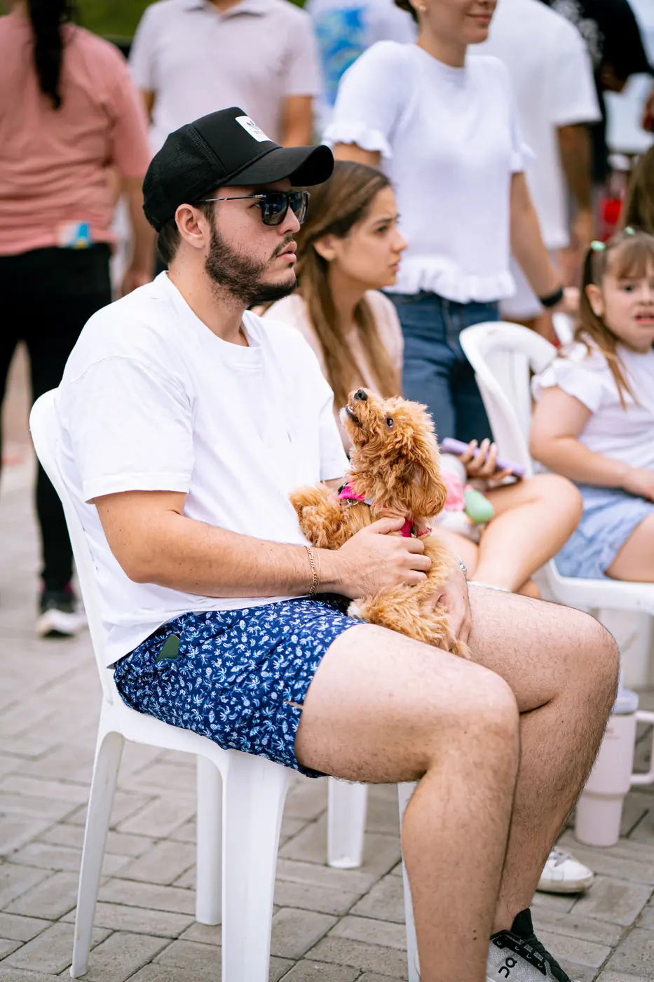 Hombre sentado en una silla con un perrito en el regazo durante un evento en Padelmar