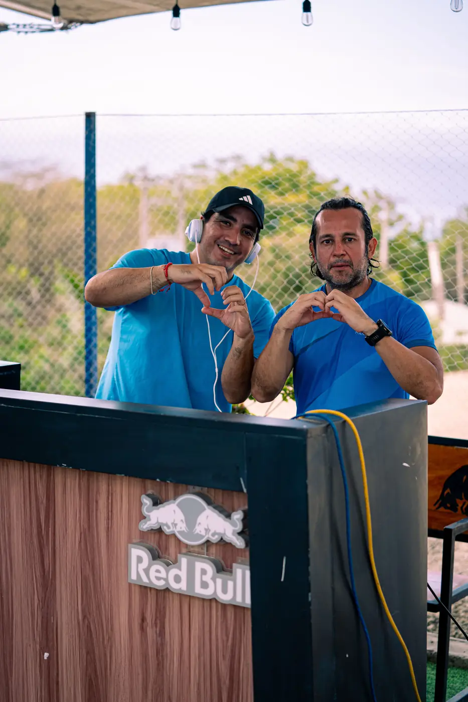Dos personas haciendo un corazón con las manos detrás de una cabina de Red Bull