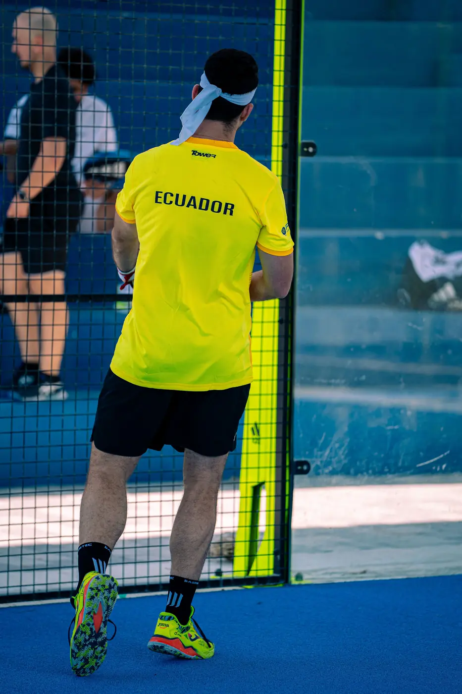 Jugador con la camiseta amarilla de Ecuador visto de espaldas junto a la cancha