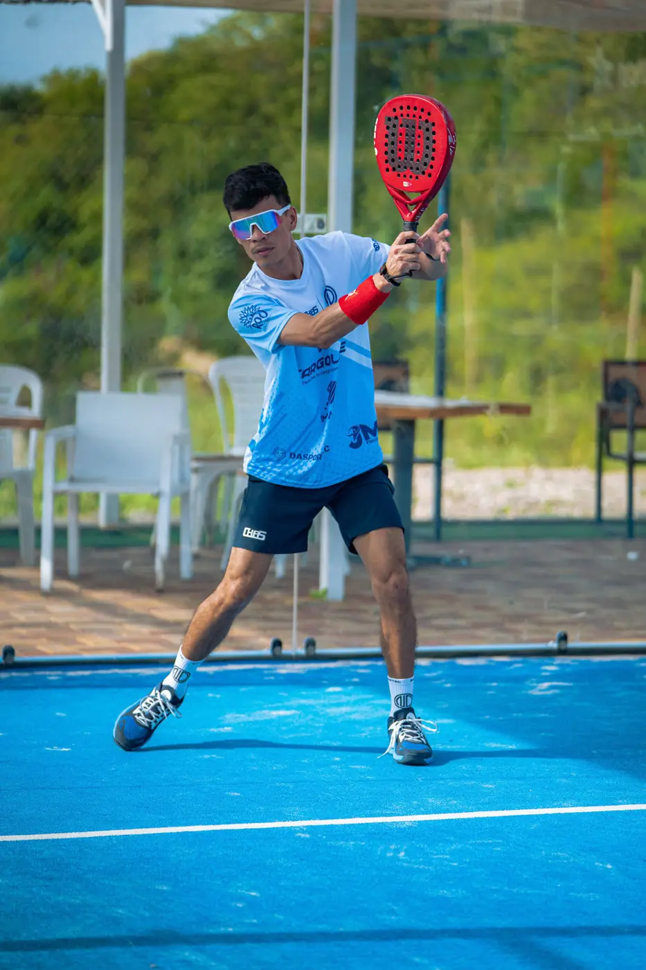 Jugador con gafas de sol preparando un revés durante un torneo